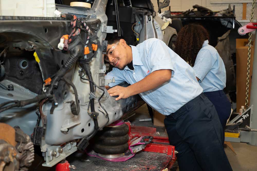 Two students working on a car.